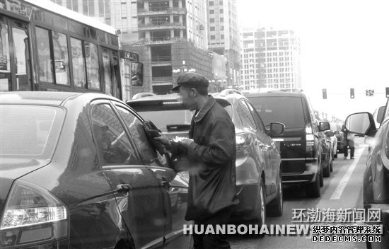 在建設(shè)路新華道路口“擦車”的行乞者。田菲菲攝